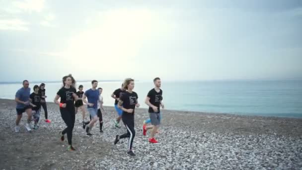 Group of sportsmen jogging along the sea slow motion — Stock Video