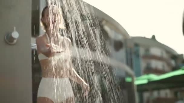 Beautiful woman in swimming costume taking a shower outdoors slow motion — Stock Video