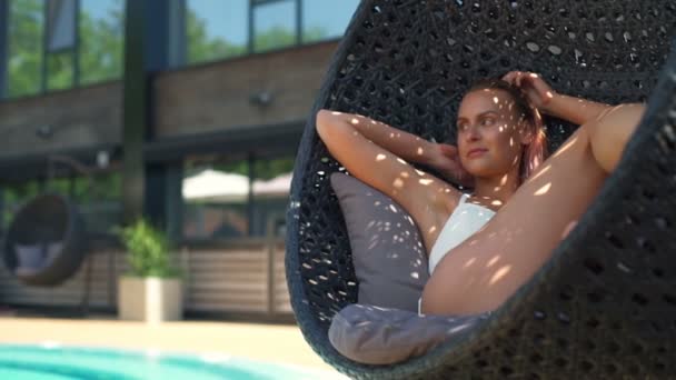 Nahaufnahme schöne Frau entspannen in Rattan runden Stuhl Zeitlupe — Stockvideo