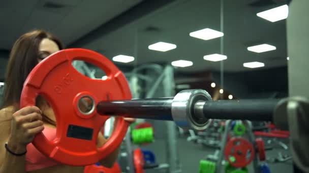 Nära upp attraktiva kvinna sätter vikter på skivstång på gym slow motion — Stockvideo