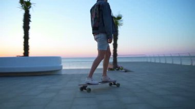 adam longboard ve deniz ağır çekim yükselen güneşin tadını çıkarmak için durur sürmek