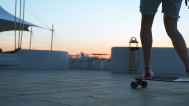 Close up male rides a longboard on seafront at sunrise slow motion — Stock Video
