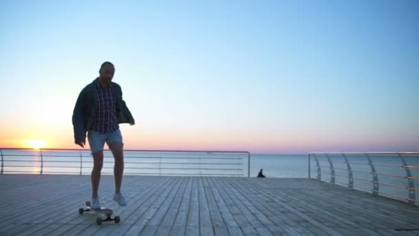Macho guapo monta un longboard en cámara lenta frente al mar — Vídeo de stock