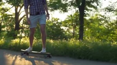 yakışıklı erkek longboard Park güneşli gün yavaş hareket üzerinde sürme