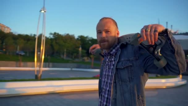 Kamera fährt Mann mit Longboard auf Schultern in Zeitlupe um — Stockvideo