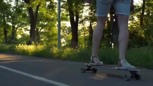 Stäng upp manliga ben på rörliga longboard i sol ljus slow motion — Stockvideo
