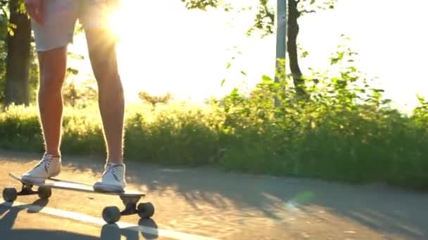 Close-up van mannelijke benen op bewegende longboard zon licht vertraagd — Stockvideo