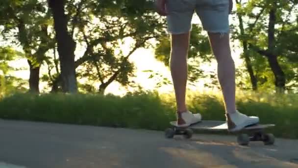 Mężczyzna nogi na przenoszenie longboard w słońcu światło zwolnionym tempie z bliska — Wideo stockowe