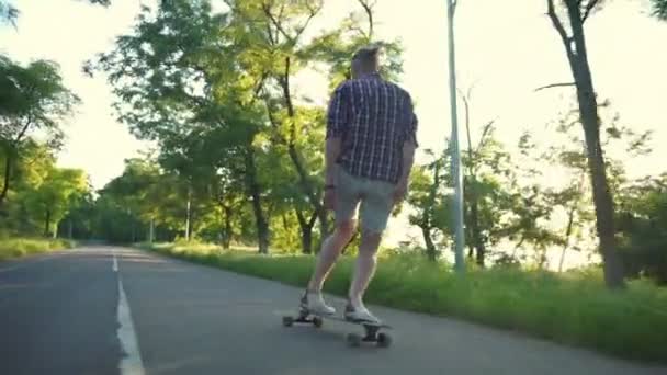 Bonito masculino equitação longboard no parque no ensolarado dia lento movimento — Vídeo de Stock