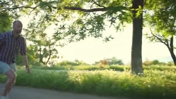 Bonito masculino equitação longboard no parque no ensolarado dia lento movimento — Vídeo de Stock