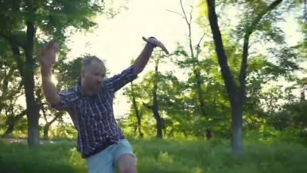 Смешной мужчина гримасит во время езды на длинной доске в парке замедленного движения — стоковое видео