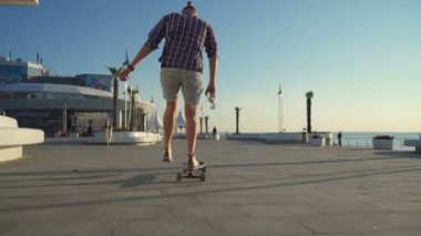 şişe su tutarak longboard üzerinde adam başka bir adam ağır çekim beşe verir