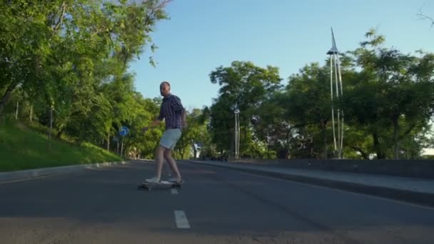 ハンサムな男性に乗って道路公園スローモーションでロングボード — ストック動画