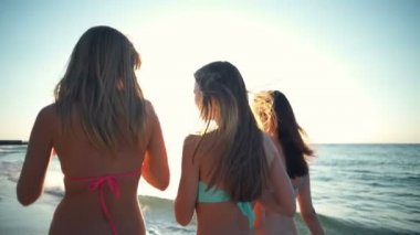 Arkadan Görünüm, üç mutlu kız bikini deniz ağır çekim yürüyüş