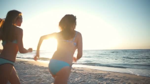 Visão traseira de três meninas em roupa de banho correndo para o mar câmera lenta — Vídeo de Stock
