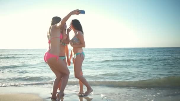 Tres chicas felices en bikini tomando selfie en el borde del mar cámara lenta — Vídeos de Stock