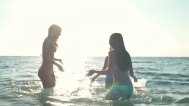 denizin güneş ışık ağır çekimde sıçramasına üç genç kadın