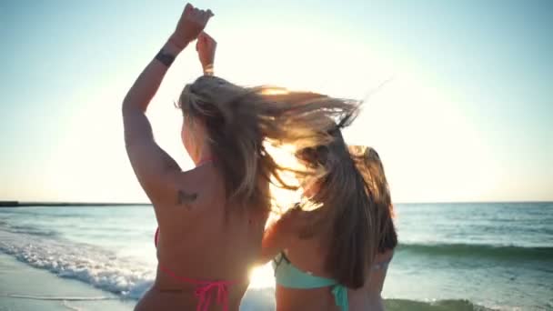 Visão traseira de três meninas felizes em biquíni andando ao longo do mar câmera lenta — Vídeo de Stock