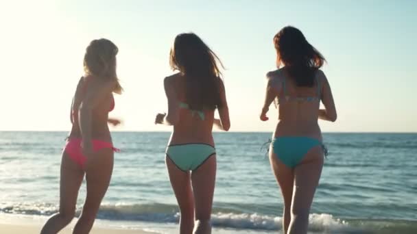 Retour vue joyeux filles en maillot de bain courir dans la mer au ralenti — Video