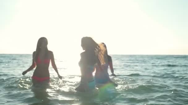 Drei junge Frauen planschen im Meer in Zeitlupe im Sonnenlicht — Stockvideo