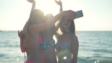Üç mutlu kız bikini plaj güneş ışık ağır çekimde selfie yapmak