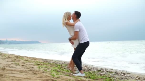 Człowiek, podnoszenie, spinning, całując jego kobieta na plaży zwolnionym tempie — Wideo stockowe