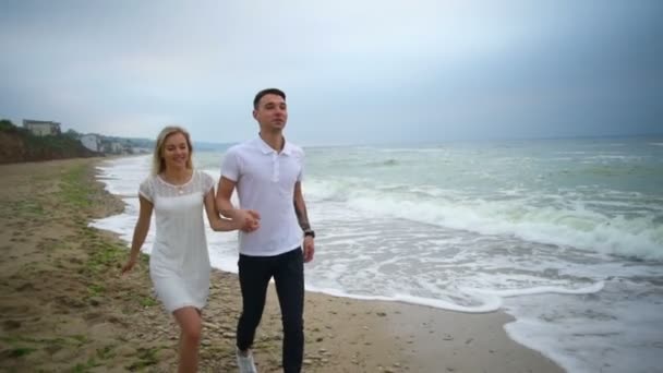 Feliz joven pareja corriendo a lo largo del mar cámara lenta — Vídeo de stock