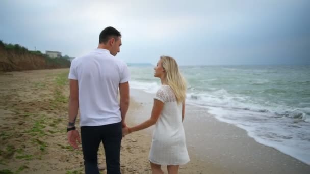 Achteraanzicht romantische wandeling voor jong koppel op het strand slow motion — Stockvideo