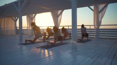 bir grup insan tarafından deniz pratik yoga şafak yavaş hareket, terasta