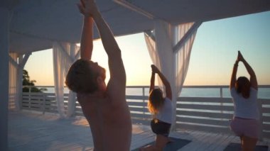 Grup yoga sınıfı tarafından şafak ağır çekim denizde terasta kapatın