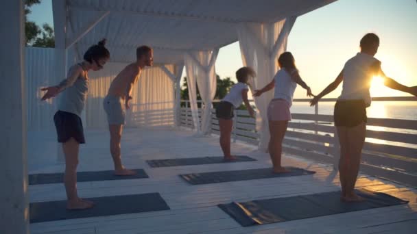 Gruppe von Menschen praktiziert Yoga auf der Terrasse im Morgengrauen Zeitlupe — Stockvideo