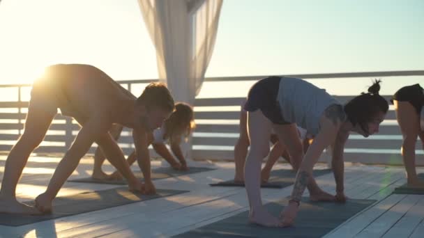 Group of people doing yoga on terrace in rays of dawn slow motion — Stock Video