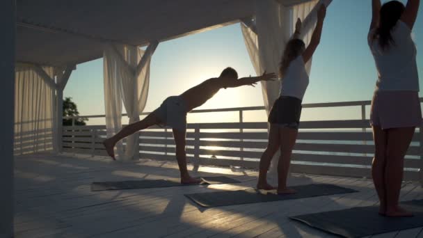 Personnes faisant asana dans une rangée un par un dans les rayons de l'aube au ralenti — Video