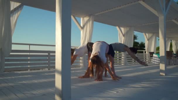 Mujeres jóvenes de pie en círculo y practicando yoga en la terraza de cámara lenta — Vídeos de Stock