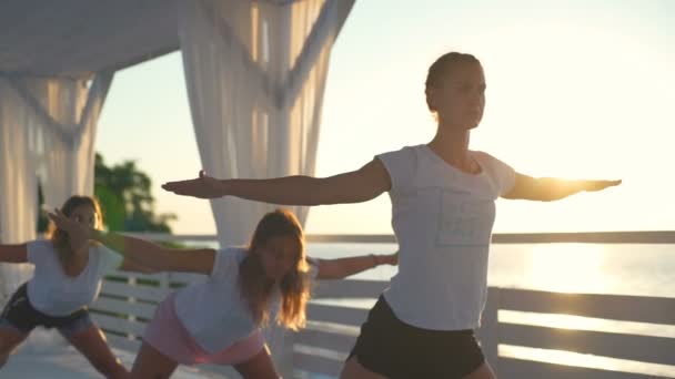 Tre donne che praticano yoga in terrazza all'alba rallentatore — Video Stock