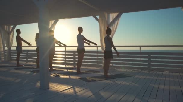 Grupp yogapass på terrassen i strålar från dawn ultrarapid — Stockvideo