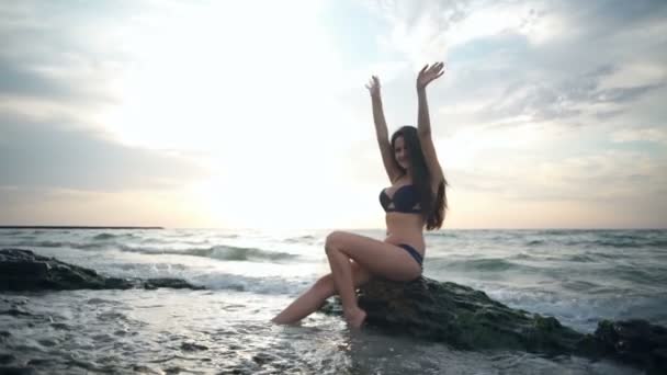 Радісна жінка в бікіні піднімає руки з морем у фоновому режимі повільний рух — стокове відео