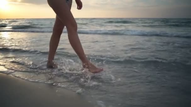 Primer plano recta piernas femeninas caminar a lo largo del borde del mar cámara lenta — Vídeo de stock