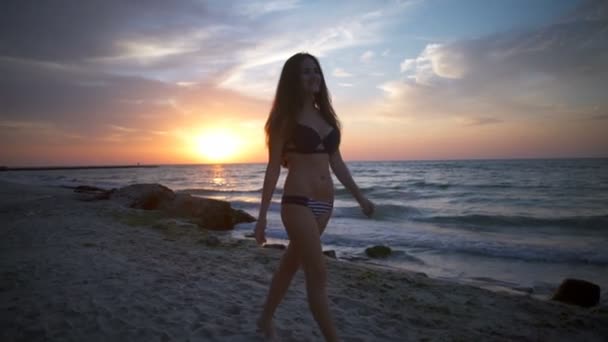 Giovane donna sorridente in bikini passeggia lungo la spiaggia slow motion — Video Stock