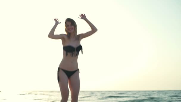 Krásná mladá dívka v plavky s úsměvem, skoky, chůze u moře při západu slunce