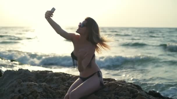 Junges schönes Mädchen in Badebekleidung und Sonnenbrille lächelt, posiert, macht Selfie — Stockvideo