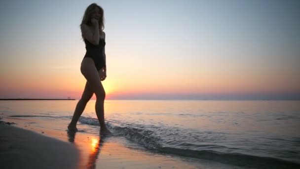 Junges schönes Mädchen in Badebekleidung, lächelnd, beim Sonnenaufgang am Meer — Stockvideo