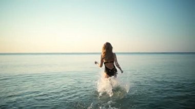 Genç güzel kız gülümseyerek, denizde kaçan Mayo içinde. Ağır çekim.