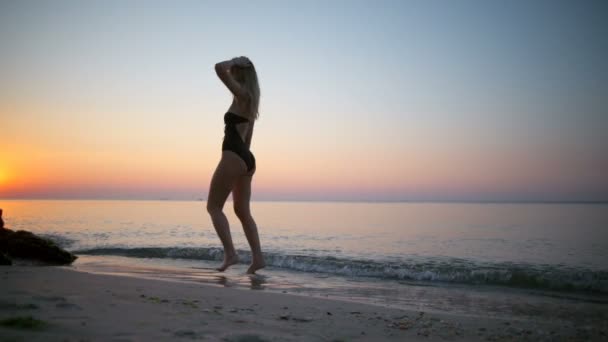 Όμορφη κοπέλα με μαγιό χαμογελώντας, στροβιλίζεται, περπάτημα στην παραλία — Αρχείο Βίντεο