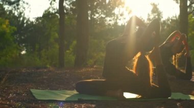 Pratik yoga gün batımında Dhanurasana ağır çekim ormanda kızlar