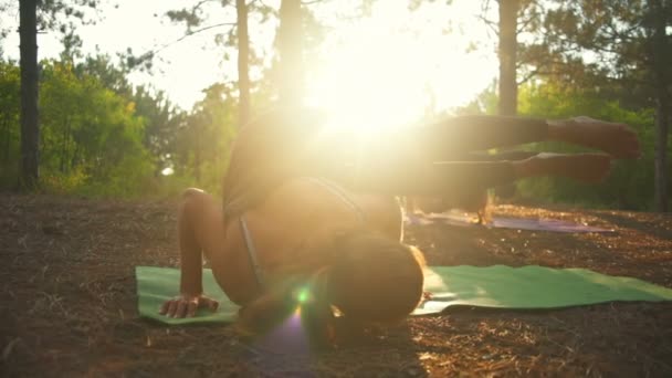 Mädchen praktizieren Yoga bei Sonnenuntergang im Wald Parshva Bakasana Zeitlupe — Stockvideo
