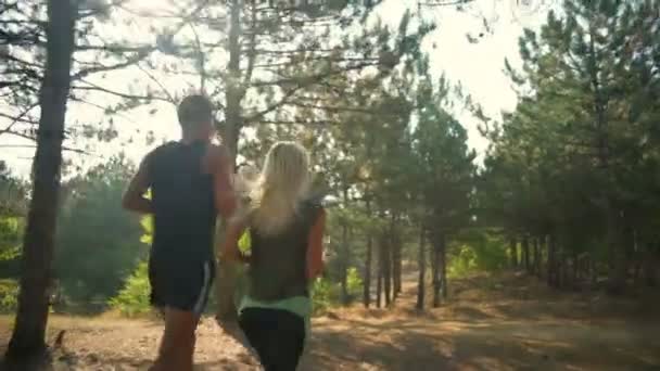 Спортивная пара бегает по дорожке в лесу Медленное движение назад — стоковое видео