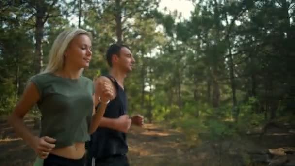 Hermosa pareja deportiva sonriendo trotando en el bosque en cámara lenta — Vídeo de stock