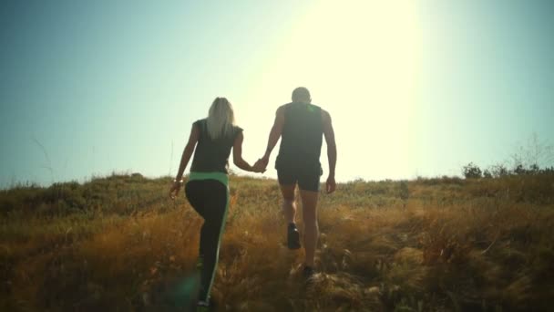 Sportive ζευγάρι ανεβαίνει το λόφο κρατώντας τα χέρια αργή κίνηση πίσω όψη — Αρχείο Βίντεο