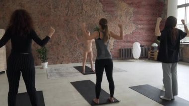 Yakışıklı yoga öğretmeni öğrencilere vinyasa ve nefes tekniklerini gösteriyor.